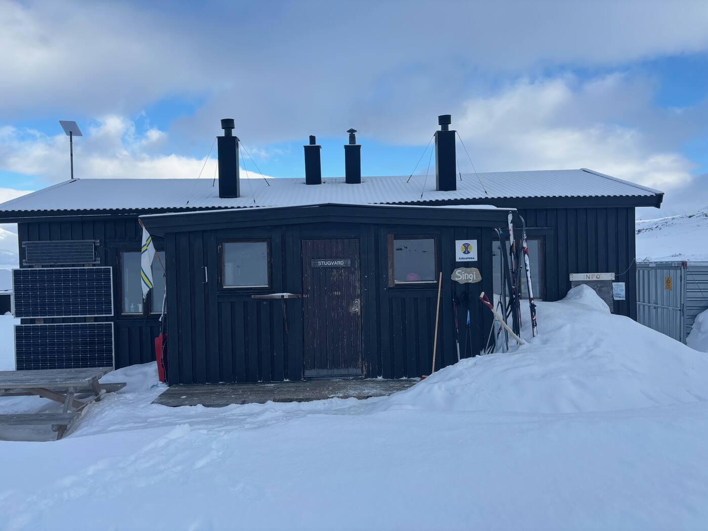 STF Singi, porte Stugvärd, panneaux solaires et skis contre le mur