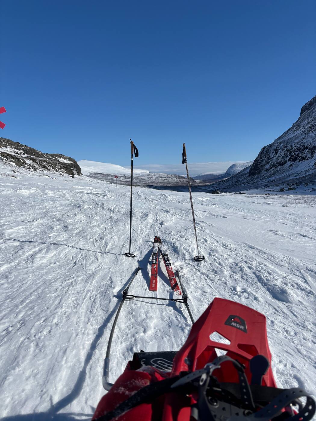 Vue depuis la pulka : skis, bâtons, ciel bleu